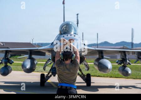 Senior Airman Catherine Bernard delle U.S. Air Force, assistente capo equipaggio dedicato del 35° Squadrone da caccia, dirige un F-16 Fighting delle U.S. Air Force Foto Stock