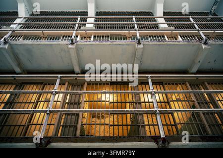 Guarda verso le finestre sbarrate e la facciata in cemento di un edificio a più piani che ospita blocchi di celle carcerarie Foto Stock