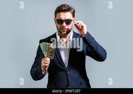 Uomo d'affari incognito con occhiali da sole scuri tiene dollari. Uomo incognito con dollari. Ritratto in contanti con dirigente incognito. Affare segreto Foto Stock