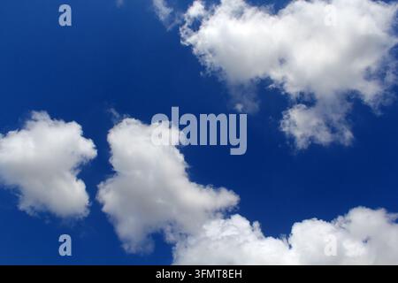 Nuvole bianche e soffici sparse su uno sfondo di cielo blu profondo in una giornata serena Foto Stock