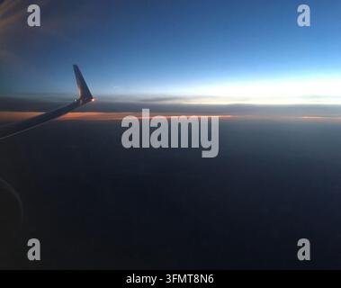 Vista aerea di un tramonto o alba dal finestrino di un aereo, probabilmente scattata durante un volo da PFO (Paphos, Cipro) a TLL (Tallinn, Estonia) sopra Roma Foto Stock