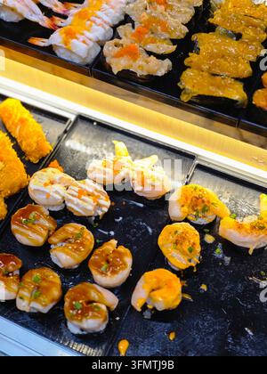 Una selezione fresca di sushi con gamberetti, caviale di salmone, salsa e guarnizione su vassoio nero Foto Stock
