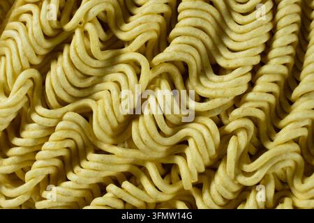 Motivo macro di noodles istantanei gialli ondulati secchi. Foto Stock