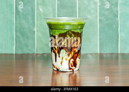 Bevanda ghiacciata al matcha con salsa di caramello che cola lungo una tazza trasparente Foto Stock