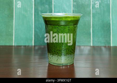 Limonata Matcha ghiacciata con texture verde screziata in una tazza trasparente su un tavolo scuro Foto Stock