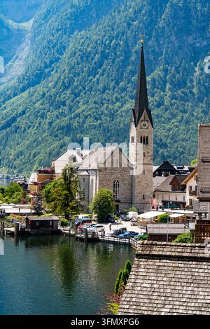 Villaggio naturale di Hallstatt sul lago delle Alpi e acqua in Austria. Vecchia chiesa. Sfondo di collina verde Foto Stock