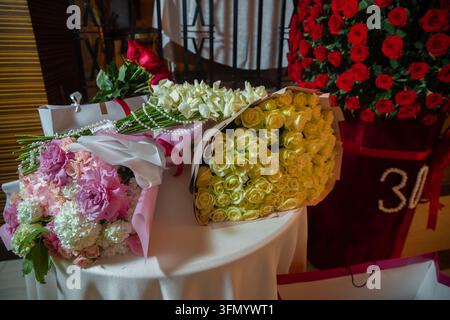 Regali eleganti decorati con perle preparati per un evento anniversario speciale. Mazzi di fiori di lusso assortiti compresi rose bianche e rosa Foto Stock