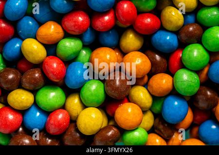 Prima vista di pezzi di caramelle rotondi assortiti in colori vivaci rosso, blu, verde, giallo, arancione e marrone, creando uno sfondo di dolci vivace Foto Stock