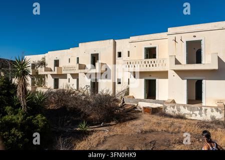 Grande facciata abbandonata con file di stanze vuote e balconi in cemento rotti su una struttura trascurata a Creta, Grecia Foto Stock