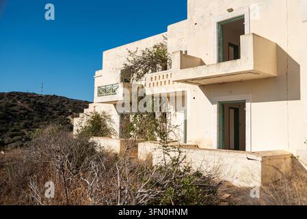 Grande facciata abbandonata con file di stanze vuote e balconi in cemento rotti su una struttura trascurata a Creta, Grecia Foto Stock