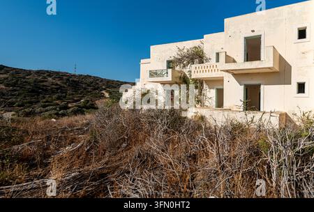 Grande facciata abbandonata con file di stanze vuote e balconi in cemento rotti su una struttura trascurata a Creta, Grecia Foto Stock