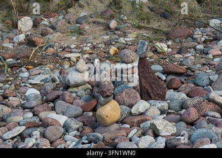 Piccoli cumuli di pietra su una spiaggia di ciottoli multicolori Foto Stock