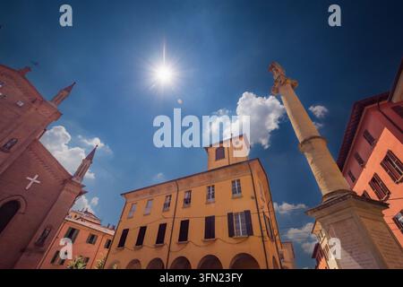 Bologna, Italia - 17 maggio 2018: Vista di una piazza storica a Bologna con un'alta colonna di pietra, edifici tradizionali gialli e rossi e un sole splendente in Foto Stock