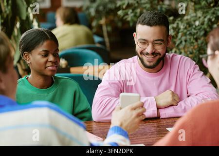 Gruppo multiculturale di amici che guardano uno smartphone in un caffè Foto Stock