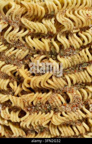 Primo piano di spaghetti istantanei crudi e ondulati ricoperti da una salsa piccante. Foto Stock
