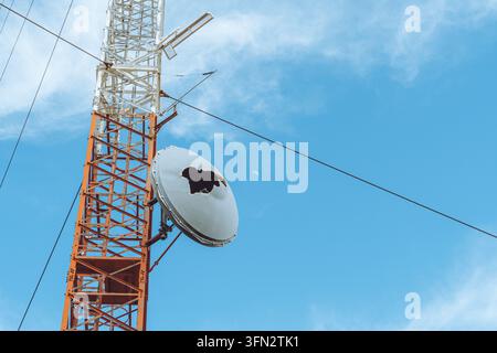 Antenna satellitare danneggiata su torre di telecomunicazioni a Serra da Lousa, Portogallo sotto un cielo blu Foto Stock