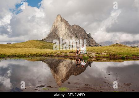 I visitatori godono della serenità del Passo Giau nelle Dolomiti, Italia, mentre i maestosi picchi si riflettono in uno stagno tranquillo. Foto Stock