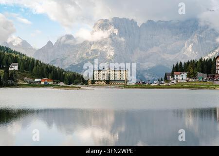 Scopri la serenità del Lago di Misurina, incastonato nelle Dolomiti, Italia. Vette montuose mozzafiato si ergono maestose sullo sfondo, cr Foto Stock