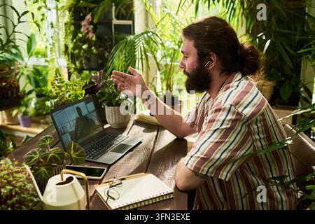 Uomo che ha una videochiamata sul laptop lavorando da remoto da casa Foto Stock