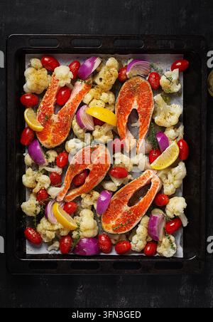 Salmone fresco con verdure pronto per la cottura al forno. Vista dall’alto, verticale Foto Stock