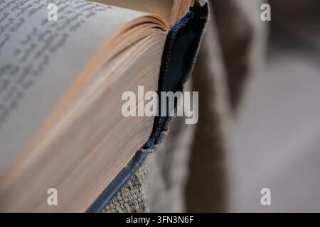 Libro antico aperto con pagine invecchiate, che mostra testo sfocato e il dorso esposto per la lettura e l'apprendimento Foto Stock