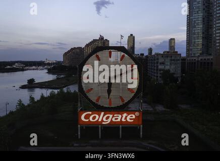 Vista aerea dell'orologio storico Colgate illuminato al crepuscolo con lo skyline di Jersey City e il lungofiume dell'Hudson River sullo sfondo a Jersey City Foto Stock