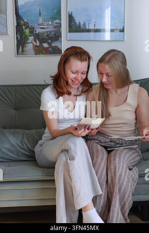 Madre e figlia condividono un album di foto a casa, illustrando relazioni strette, tempo di qualità e connessione emotiva. Foto Stock