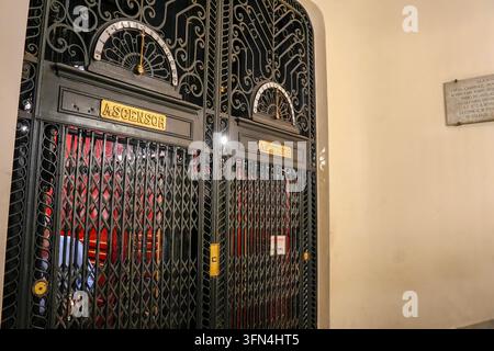 Un ascensore in ferro battuto Art Nouveau magnificamente conservato con decorazioni a volute, indicatori di piano in ottone e interno rosso in un Buenos Ai storico Foto Stock