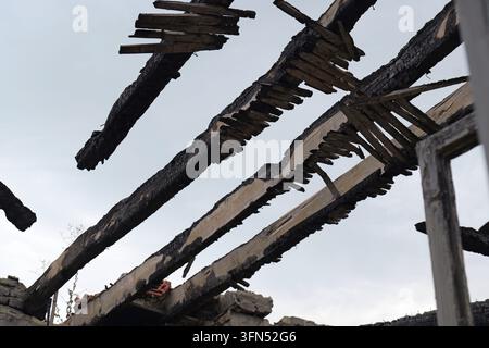 Travi del tetto in legno carbonizzate ed elementi strutturali di una casa dopo un incendio devastante, che mostrano danni estesi e distruzione causati dal disastro naturale Foto Stock