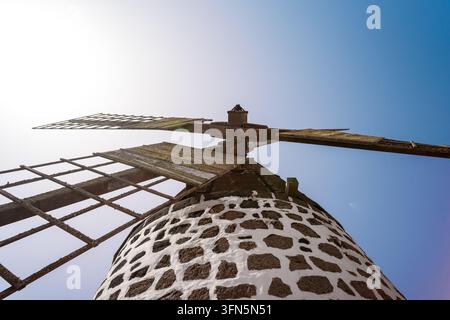 Una vista drammatica dall'alto guarda verso le vele e la torre in pietra di un mulino a vento tradizionale contro il cielo, Villaverde, La Oliva, Fuerteventura Foto Stock