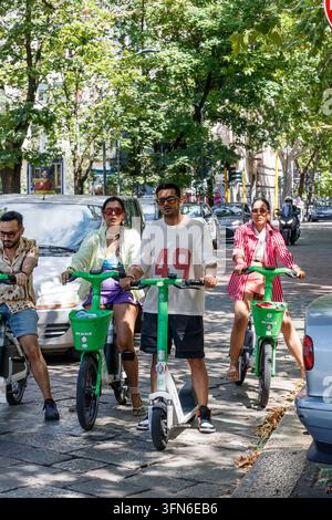Persone in sella a scooter elettrici Lime e biciclette Lime su una strada in Europa Foto Stock
