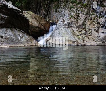Fiume Sanzhanxi a Hualien, Taiwan. Una piccola cascata sfocia in una chiara piscina naturale. Formazioni rocciose impervie circondano il ruscello. Foto Stock