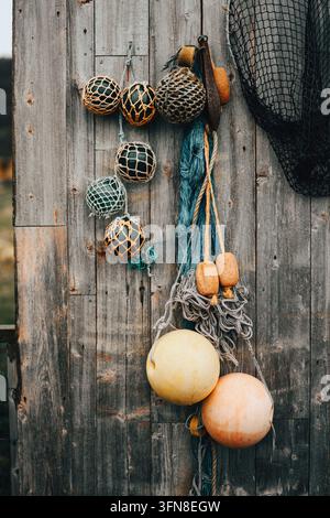 Assortimento di reti da pesca e boe su un muro di legno rustico Foto Stock