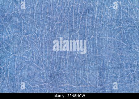 Tessuto denim blu con pieghe e sfondo di jeans vintage consumato Foto Stock