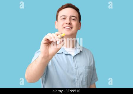Educazione e apprendimento interattivo, giovane uomo che scrive su vetro con un pennarello per una presentazione aziendale o istruzione in classe isolata su sfondo blu Foto Stock