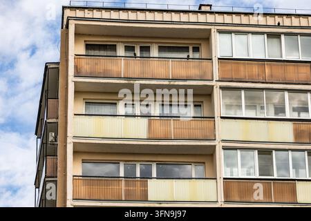 La facciata esterna di un edificio residenziale a più piani presenta pannelli per balconi tinti e grandi finestre sotto un cielo nuvoloso. La vista prospettica Foto Stock