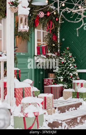 Scatole regalo di Natale con albero di pino decorato su un portico innevato Foto Stock