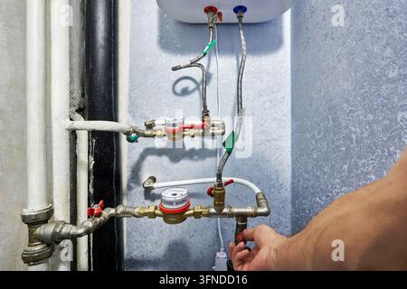 Installazione di un insieme contamisure dell'acqua e di un collettore idraulico su una parete interna durante la manutenzione della configurazione idraulica residenziale Foto Stock
