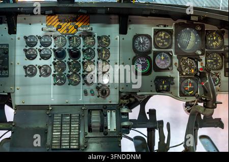 Vista ravvicinata del complesso cruscotto all'interno del cockpit di un vecchio elicottero militare, che evidenzia vari strumenti analogici, quadranti, interruttori e comandi Foto Stock