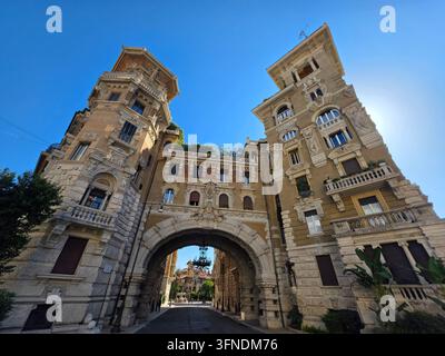 Vista drammatica in basso dell'imponente portale ad arco e delle due torri del quartiere Coppedè a Roma, Italia. Foto Stock