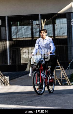 Giovane uomo in bicicletta rossa per una strada urbana Foto Stock