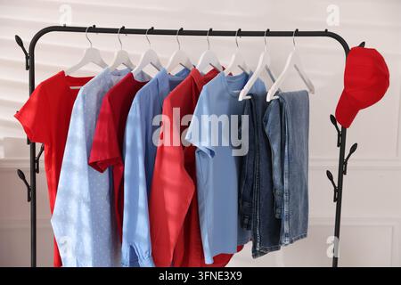 Diversi vestiti e cappellino da baseball appesi a un scaffale al chiuso Foto Stock