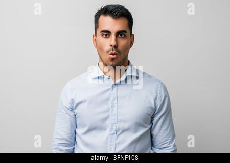 Uomo in abiti casual con espressione di sorpresa, sguardo scioccato e shock, eccitato, paura e timore — ritratto in studio che cattura una reazione sbalordita Foto Stock