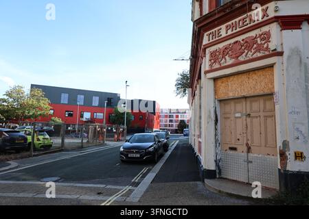 Ingresso incorniciato sotto la segnaletica The Phoenix sbiadita su un edificio storico eroso a Plymouth, Devon. Foto Stock