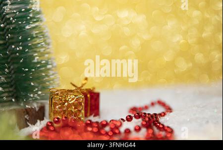 Albero di Natale in miniatura con scatole regalo e perline rosse sulla neve artificiale Foto Stock