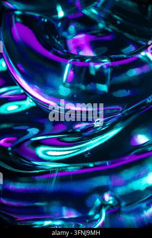 Composizione astratta in primo piano di forme in vetro trasparente con vivaci riflessi neon ciano, blu e magenta, creando uno sfondo futuristico luminoso Foto Stock