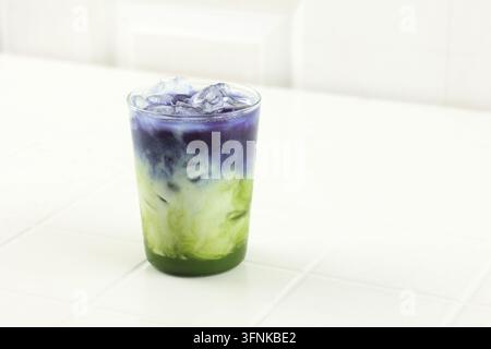 Latte matcha con tè dei butterfly pea su tavolo bianco Foto Stock
