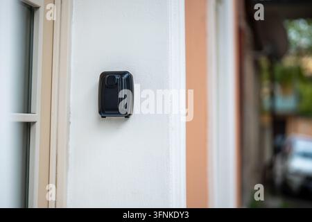 Cassetta di sicurezza nera con codice chiave all'interno, posizionata su un muro vicino al cancello d'ingresso di un edificio residenziale. Foto Stock