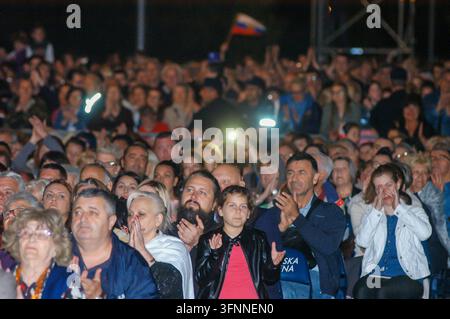 BELGRADO, SERBIA - 23 GIUGNO 2018: Grande folla seduta all'aperto di notte, che applaude e guarda una performance dal vivo sul palco con luci brillanti e illuminazioni Foto Stock