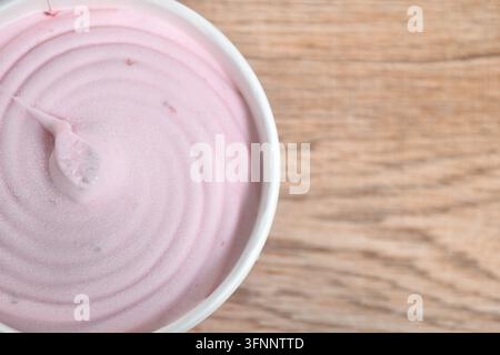 Prima piano di gelato al gusto di fragola in una coppetta di carta sul tavolo Foto Stock